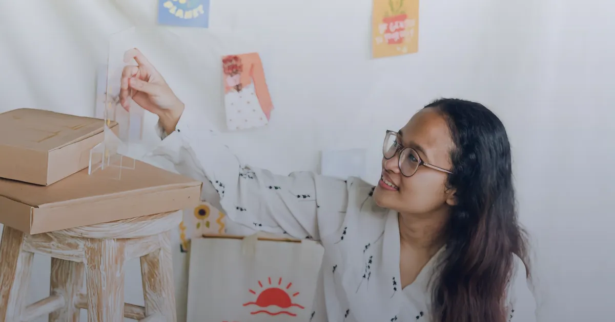 A smiling online seller in her workspace, surrounded by packed orders and product boxes