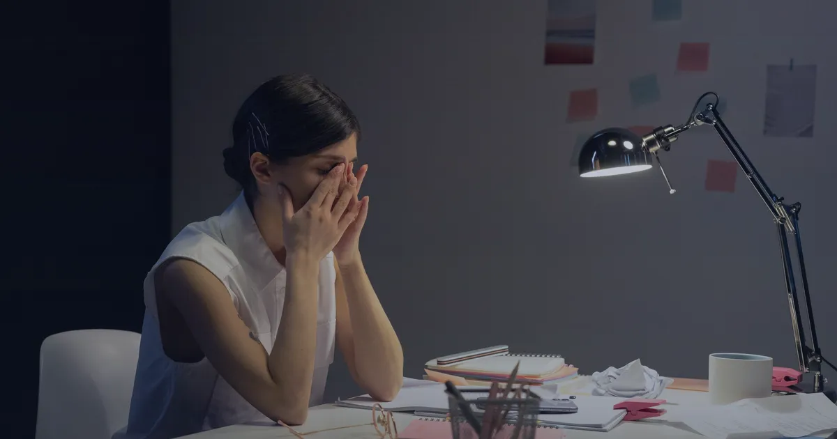 A stressed business owner at her desk late at night, head in her hands